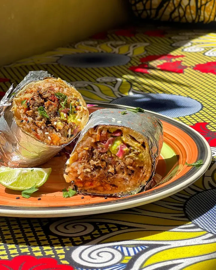 A burrito cut in half showing beef, rice and guacamole