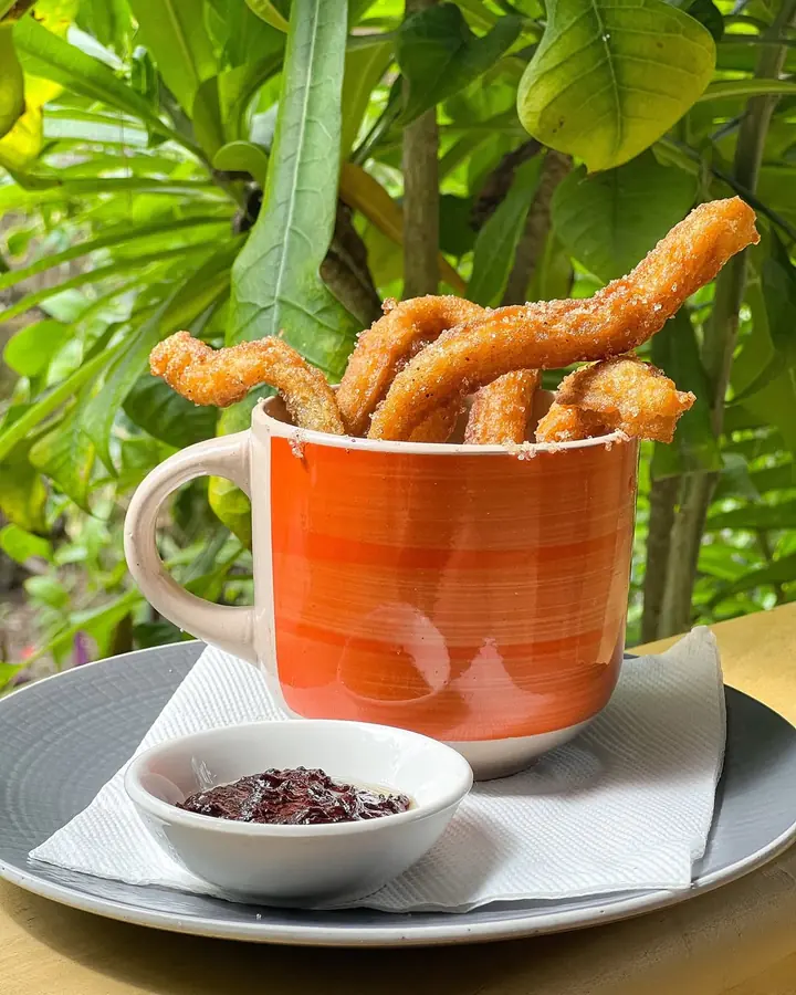 Cinnamon-sugar churros in a mug with a dipping sauce